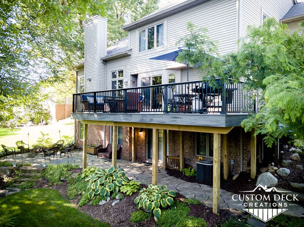 2nd story grey composite deck with unique and beautiful landscaping under the deck