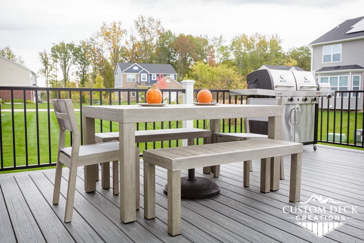 Outdoor patio table with bench and chairs on top of a grey composite deck