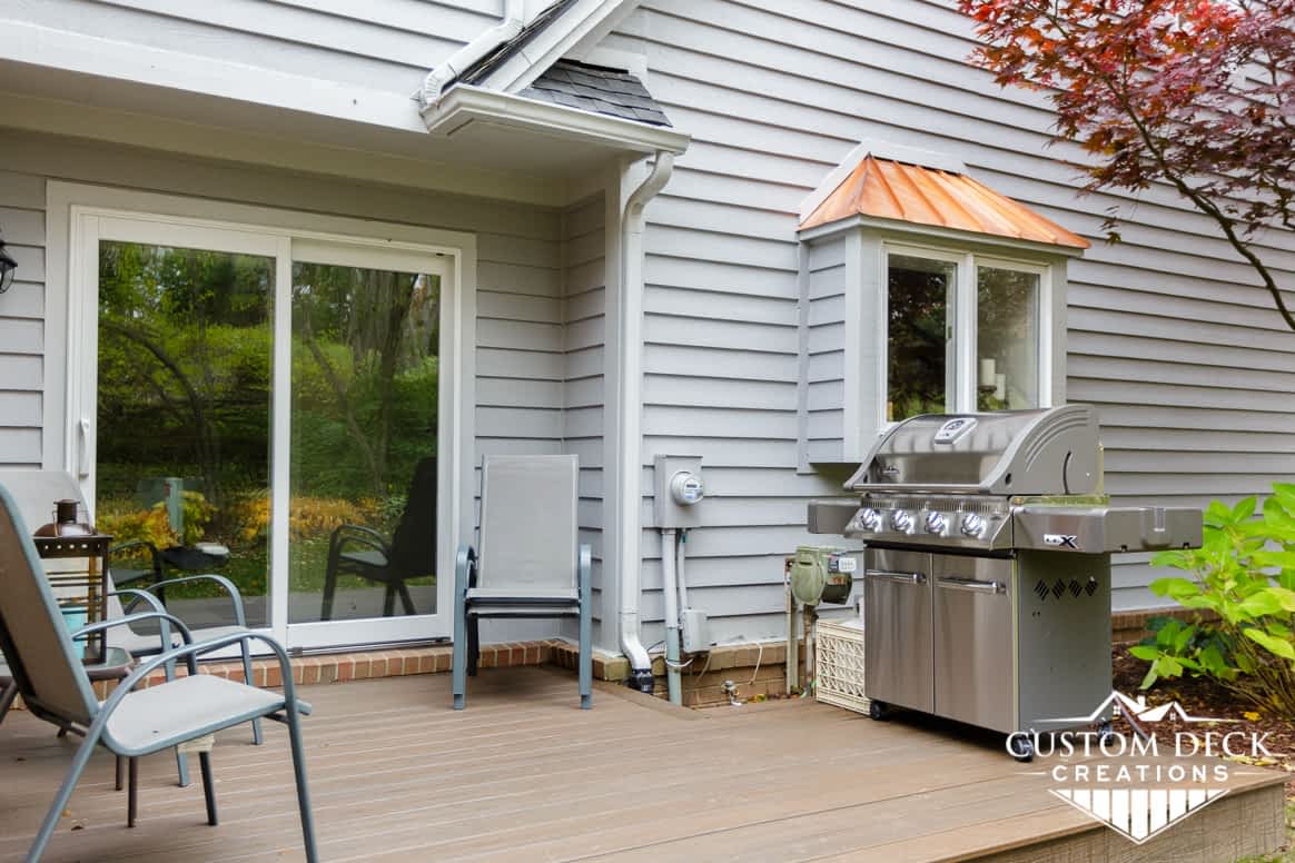 Ground level composite deck with grill and patio chairs