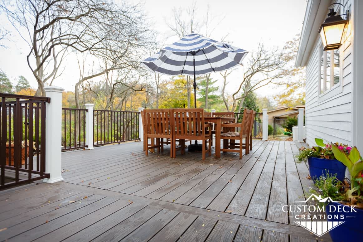 Backyard deck, brown, with railing, posts, table, chairs and umbrella