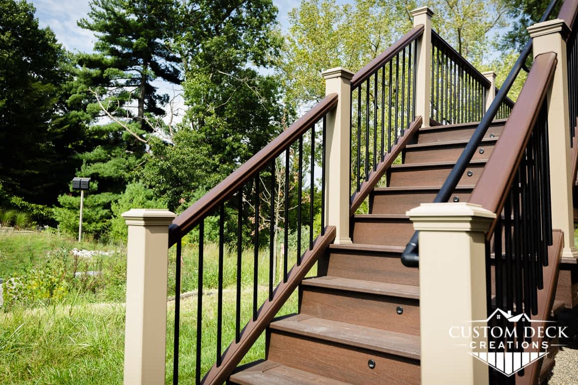 Brown outdoor stairs with lights leading up to a 2nd story backyard deck
