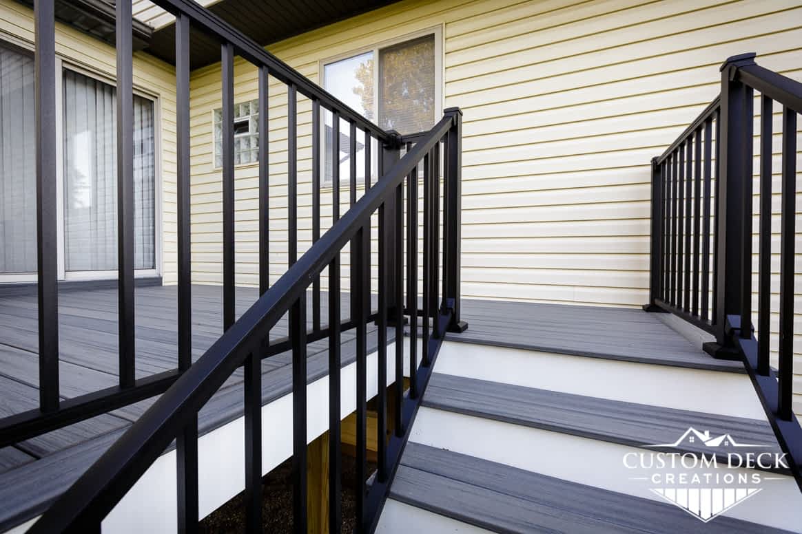 Grey and white backyard deck and stairs with black aluminum railing