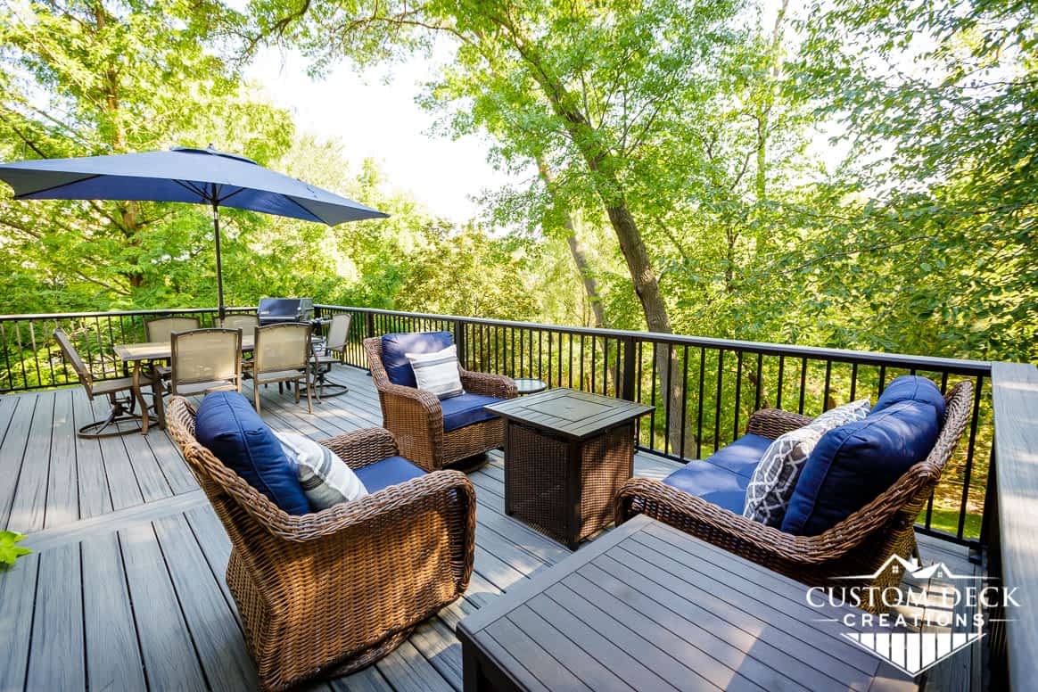 Backyard deck with furniture and a fire pit surrounded by tall trees