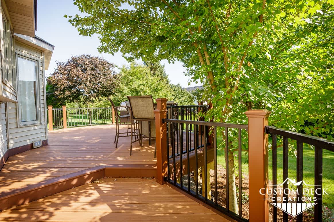 Brown backyard deck with brown and black railing, and patio furniture