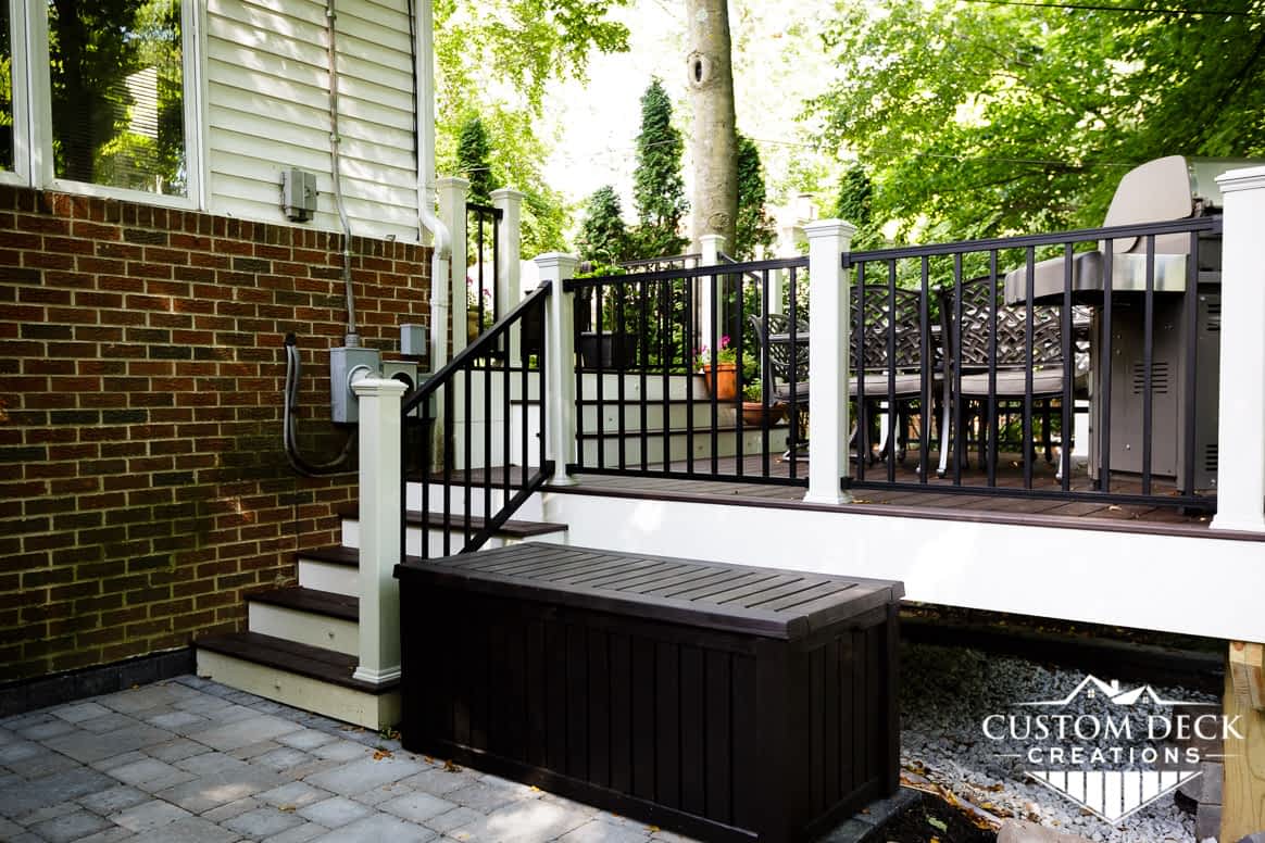 Side view of a backyard composite deck built with white fascia, black and white railing, and brown decking