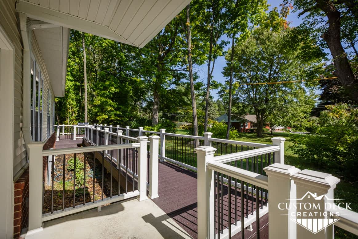 Long walkway built with brown decking and white railing behind a home