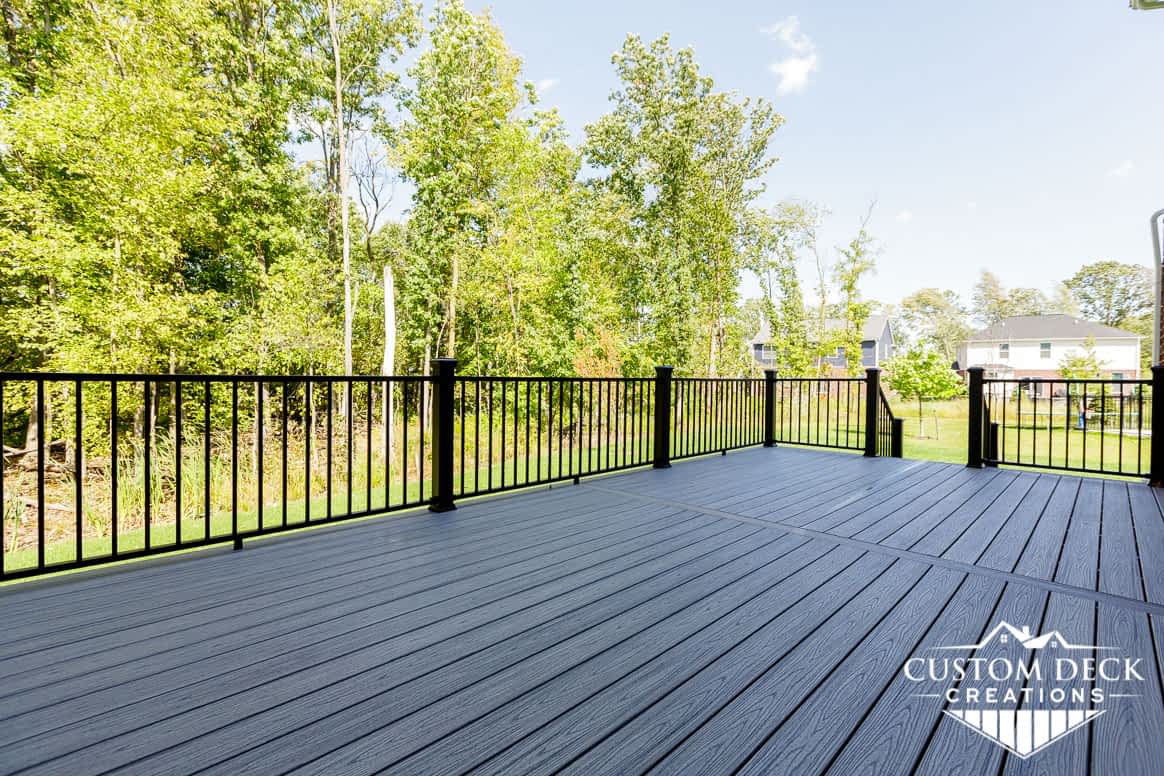 Backyard deck in grey boards and black railing built by Custom Deck Creations