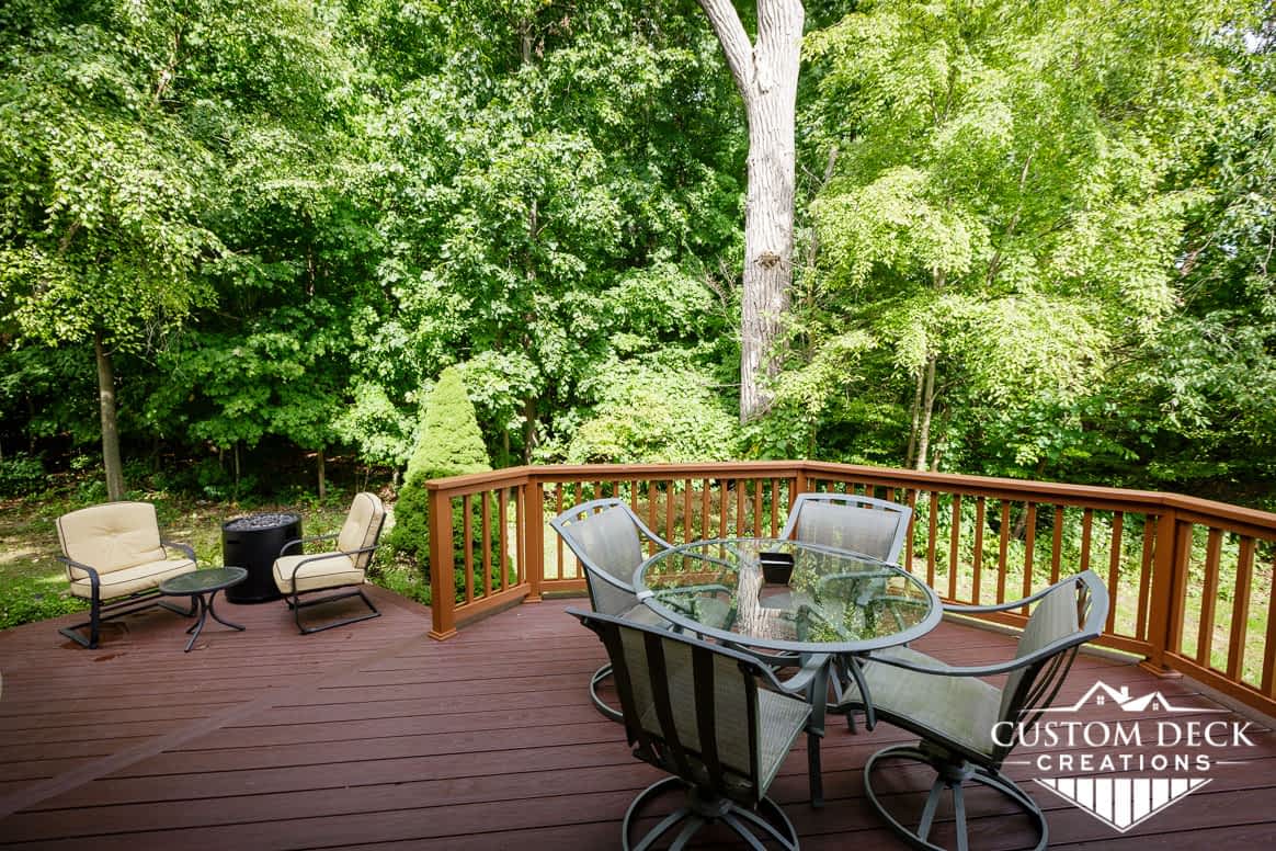 Brown deck on the back of a home with patio furniture and fire pit