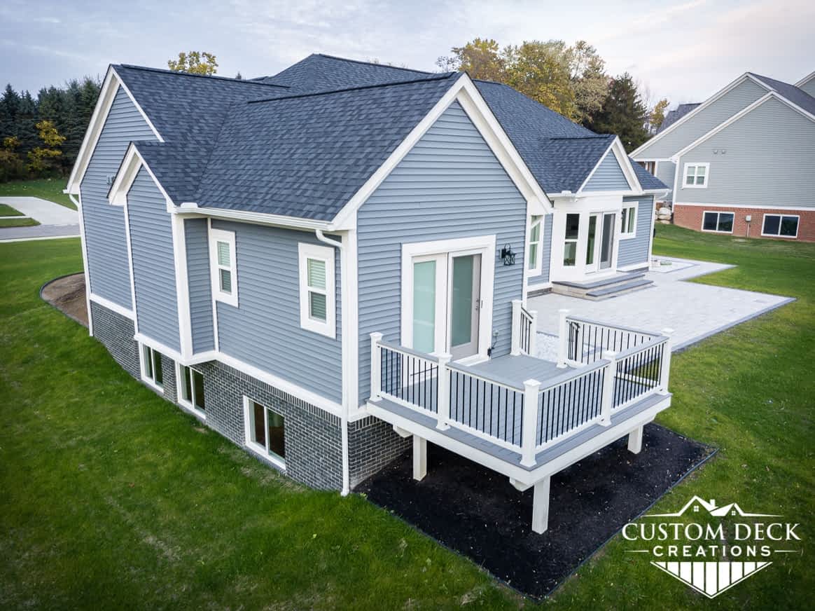 Grey backyard deck with white railing, coming off a master bedroom of a new construction house