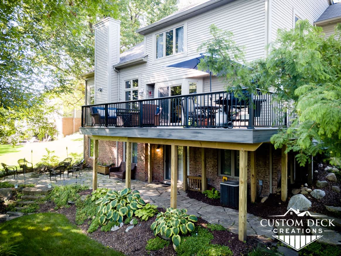 2nd story grey composite deck with unique and beautiful landscaping under the deck