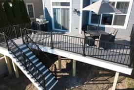 Composite deck built with Trex Island Mist and black Signature aluminum railing on new construction home - Belleville, Michigan