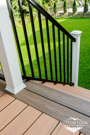 Stairs on an outdoor Trex composite deck with black and white railing with railing post cap lights