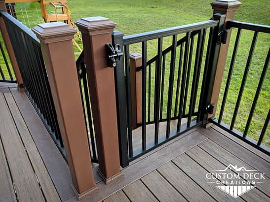 Lockable swinging aluminum gate at the top of stairs of a backyard deck
