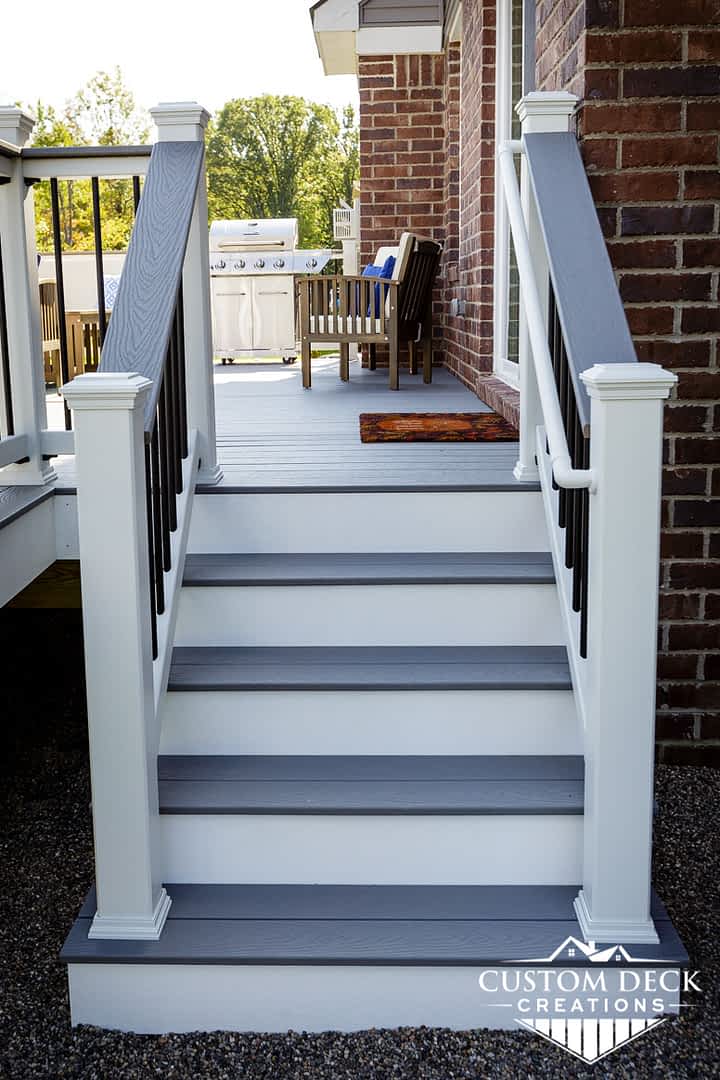 Grey and white stairs leading from backyard to a deck on the back of a new construction home