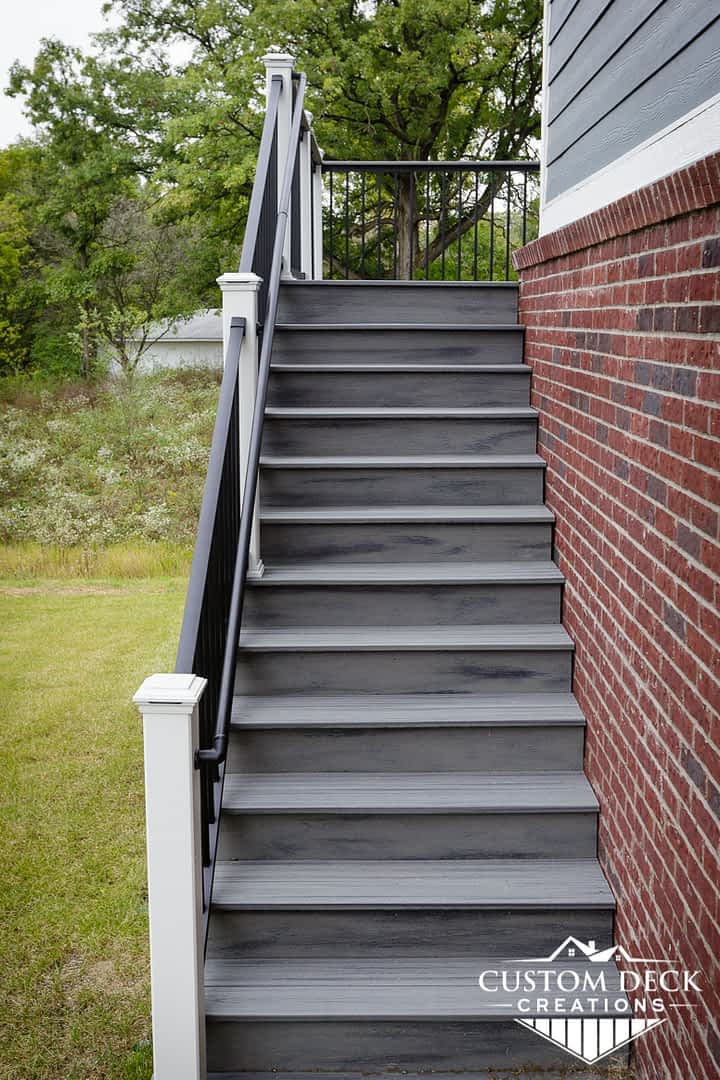 Grey stairs with black and white railing leading up to a 2nd story backyard composite deck in Canton Michigan